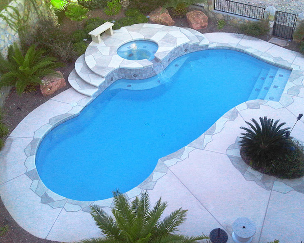 Aménagement d'une grande piscine arrière exotique sur mesure avec une dalle de béton.