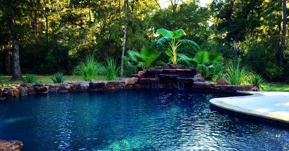 Foto di una grande piscina monocorsia tropicale personalizzata dietro casa con fontane e pavimentazioni in cemento