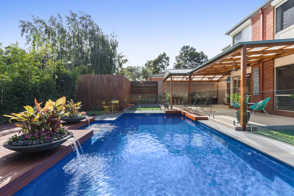 Example of a mid-sized trendy backyard rectangular natural pool fountain design in Melbourne with decking