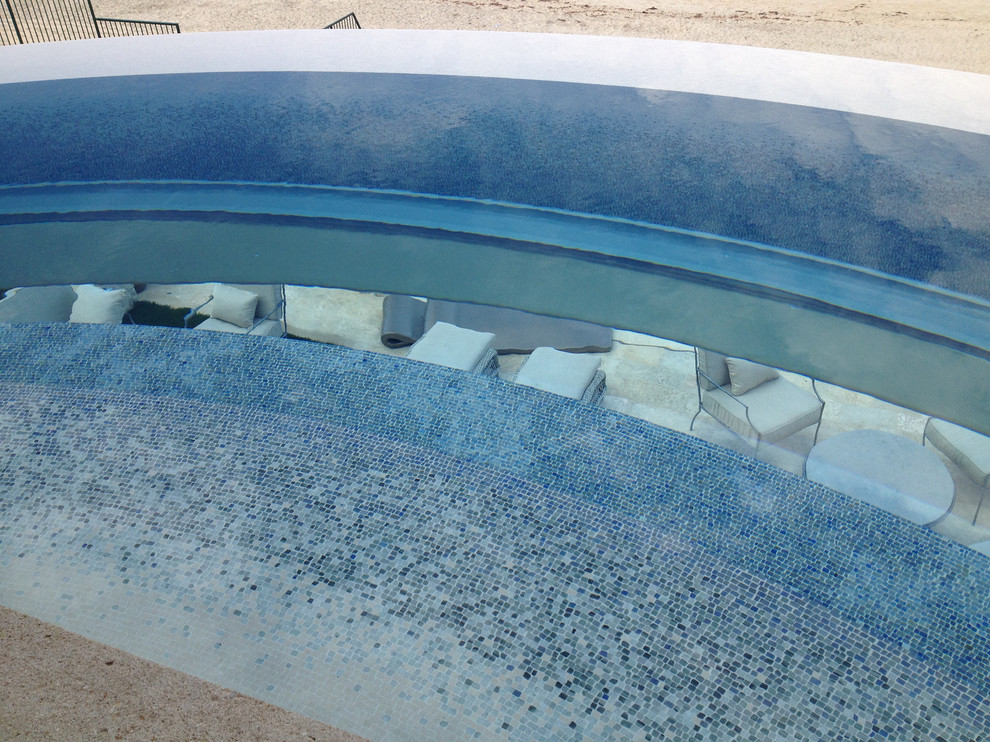 Diseño de piscina infinita contemporánea grande a medida en patio trasero con adoquines de ladrillo