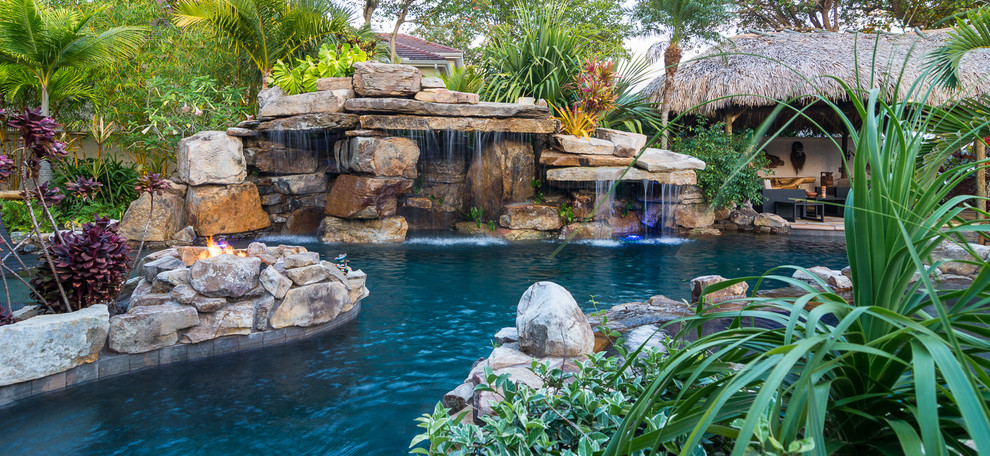Bild på en mycket stor tropisk anpassad baddamm på baksidan av huset, med en fontän och naturstensplattor