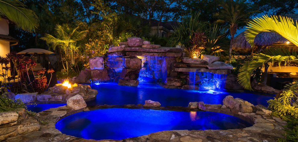 Huge island style backyard stone and custom-shaped natural hot tub photo in Tampa