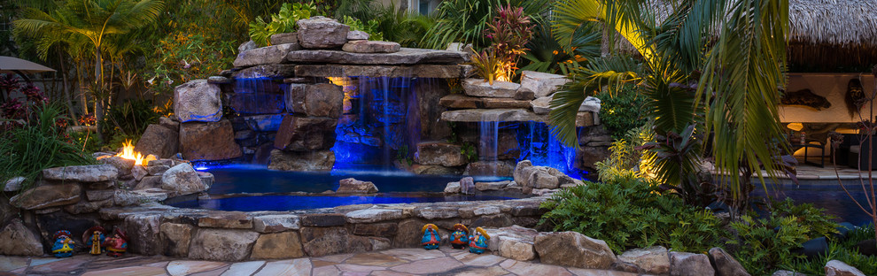 Foto de piscina con fuente natural exótica extra grande a medida en patio trasero con adoquines de piedra natural