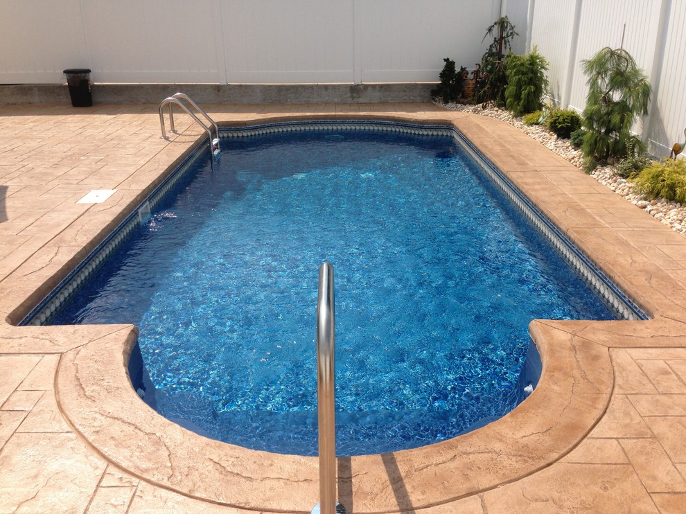 Modelo de piscina tradicional de tamaño medio a medida en patio trasero con adoquines de hormigón