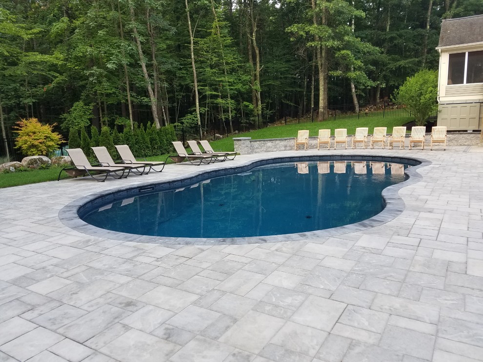 Foto de piscina alargada clásica renovada de tamaño medio a medida en patio trasero con adoquines de hormigón