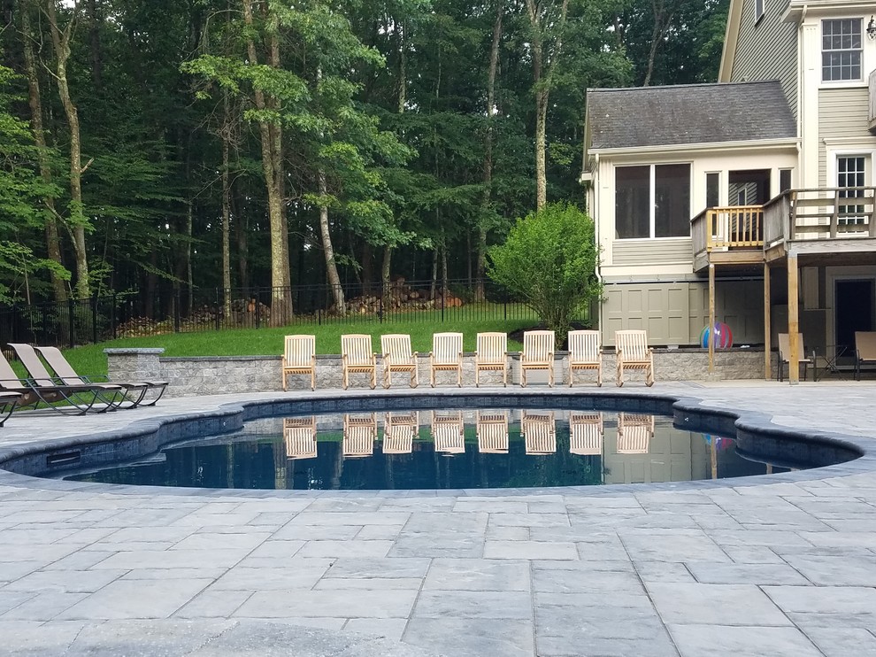 Diseño de piscina alargada tradicional renovada de tamaño medio a medida en patio trasero con adoquines de hormigón