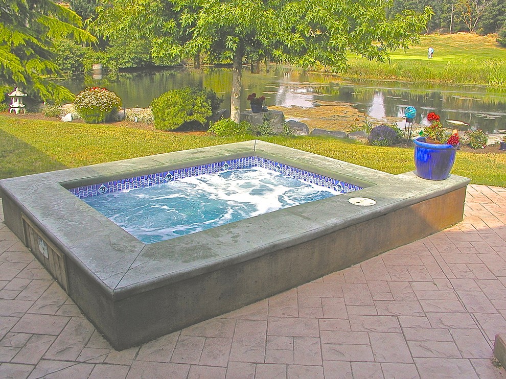 Modelo de piscinas y jacuzzis elevados modernos pequeños rectangulares en patio trasero con suelo de hormigón estampado
