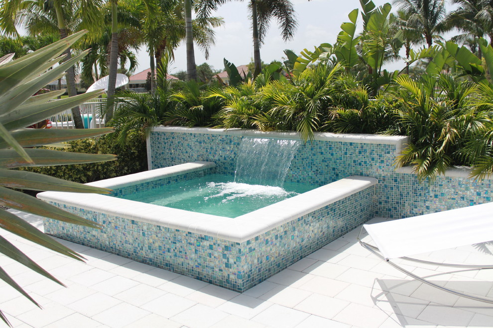 Foto de piscinas y jacuzzis elevados modernos pequeños rectangulares en patio trasero con adoquines de hormigón