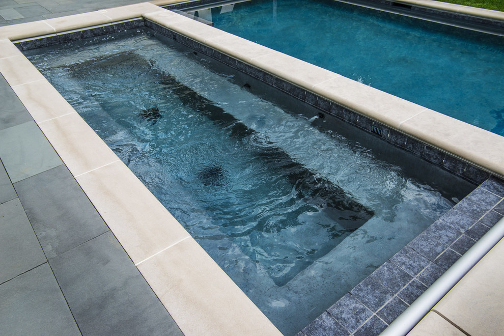 Large classic back rectangular hot tub in Chicago with natural stone paving.