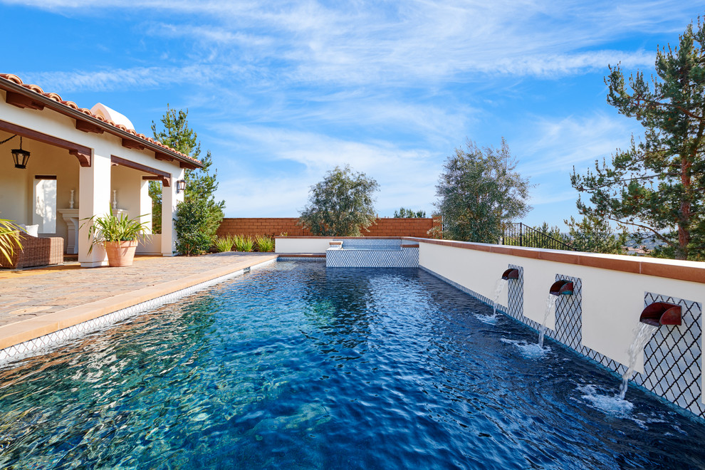Photo of a medium sized mediterranean back rectangular lengths swimming pool in Orange County with stamped concrete.
