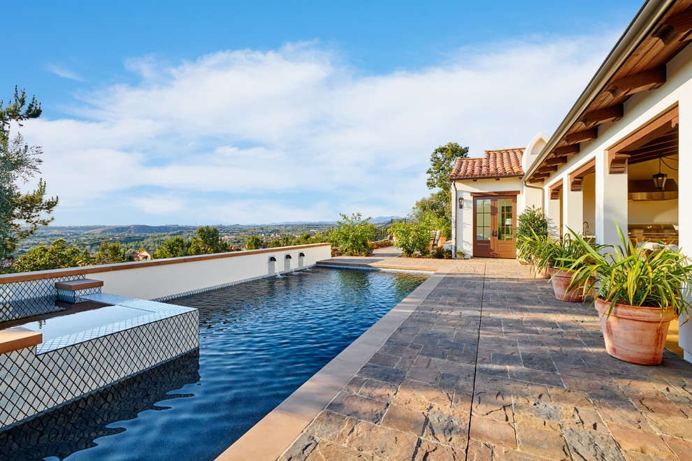 Inspiration for a medium sized mediterranean back rectangular lengths swimming pool in Orange County with natural stone paving.