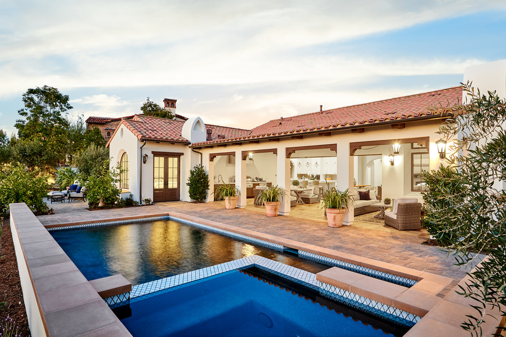 Diseño de piscina alargada mediterránea de tamaño medio rectangular en patio trasero con adoquines de piedra natural