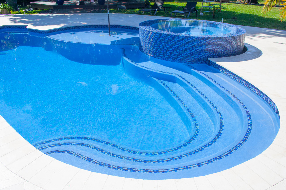 Bild på en mellanstor funkis anpassad pool på baksidan av huset, med spabad och naturstensplattor