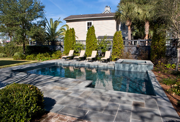 Esempio di una piscina monocorsia classica rettangolare di medie dimensioni e dietro casa con pavimentazioni in pietra naturale e una vasca idromassaggio