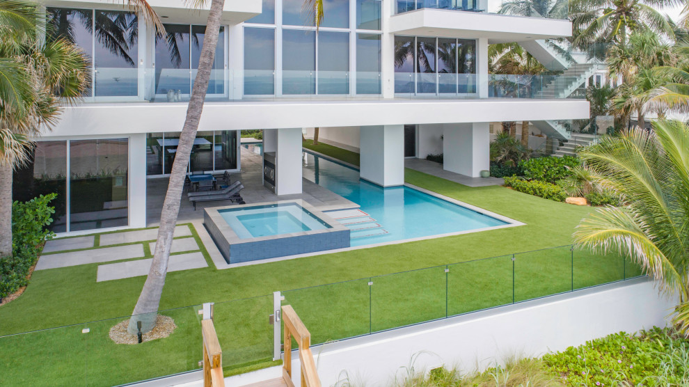 Imagen de piscinas y jacuzzis alargados minimalistas grandes a medida en patio trasero con adoquines de hormigón