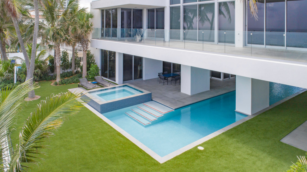 Hot tub - large modern backyard concrete paver and custom-shaped lap hot tub idea in Miami