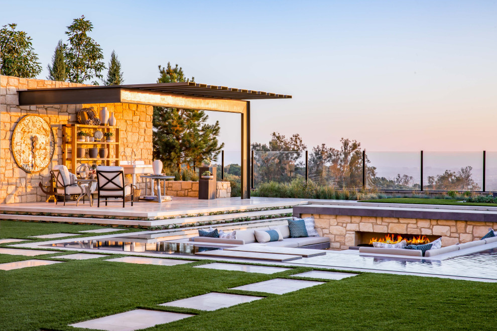 Ejemplo de piscina infinita minimalista extra grande a medida en patio trasero con privacidad y adoquines de piedra natural