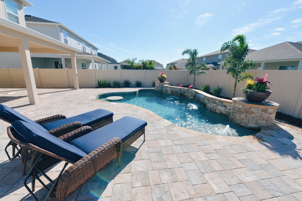 Immagine di una piscina tropicale personalizzata di medie dimensioni e dietro casa con pavimentazioni in mattoni