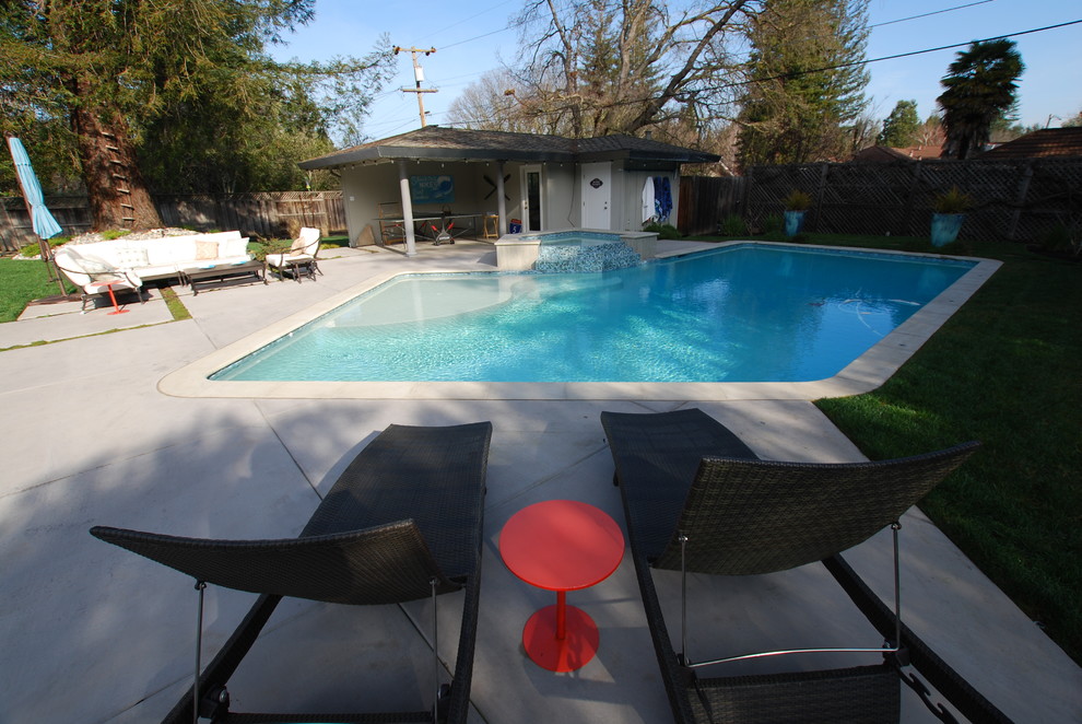 Bild på en stor funkis anpassad pool på baksidan av huset, med spabad och betongplatta