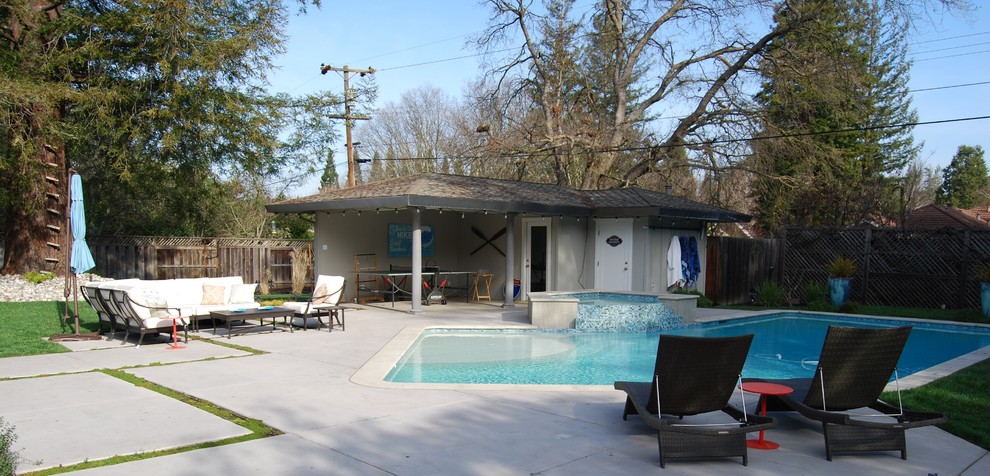 На фото: большой бассейн произвольной формы на заднем дворе в современном стиле с джакузи и покрытием из бетонных плит с