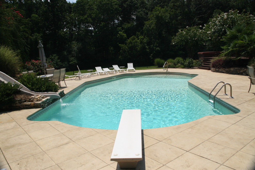 Large trendy backyard stamped concrete and l-shaped natural water slide photo in Atlanta