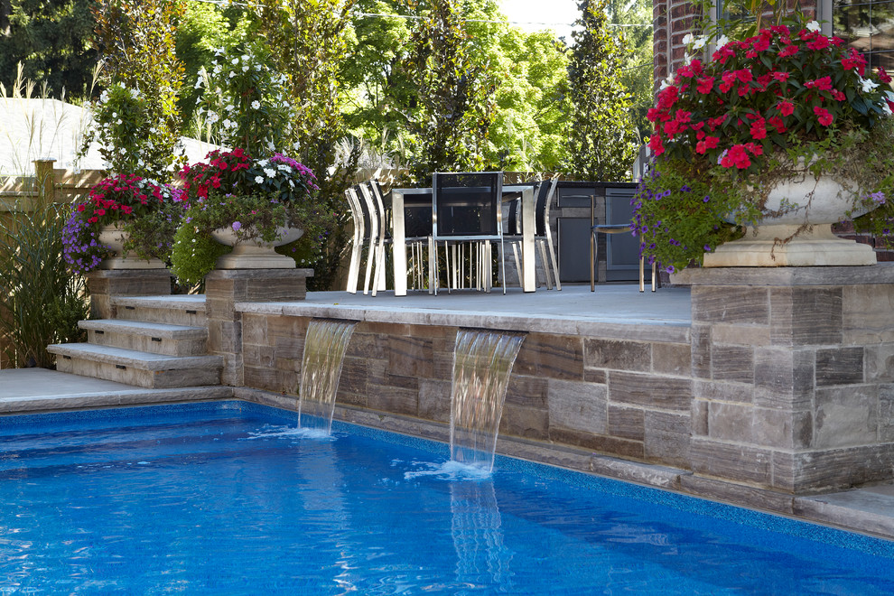 Immagine di una piscina monocorsia design rettangolare di medie dimensioni e dietro casa con fontane e pavimentazioni in cemento