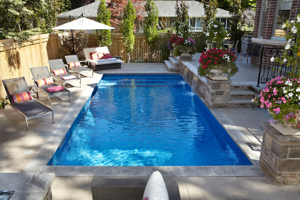 Foto de piscina con fuente alargada actual de tamaño medio rectangular en patio trasero con adoquines de hormigón