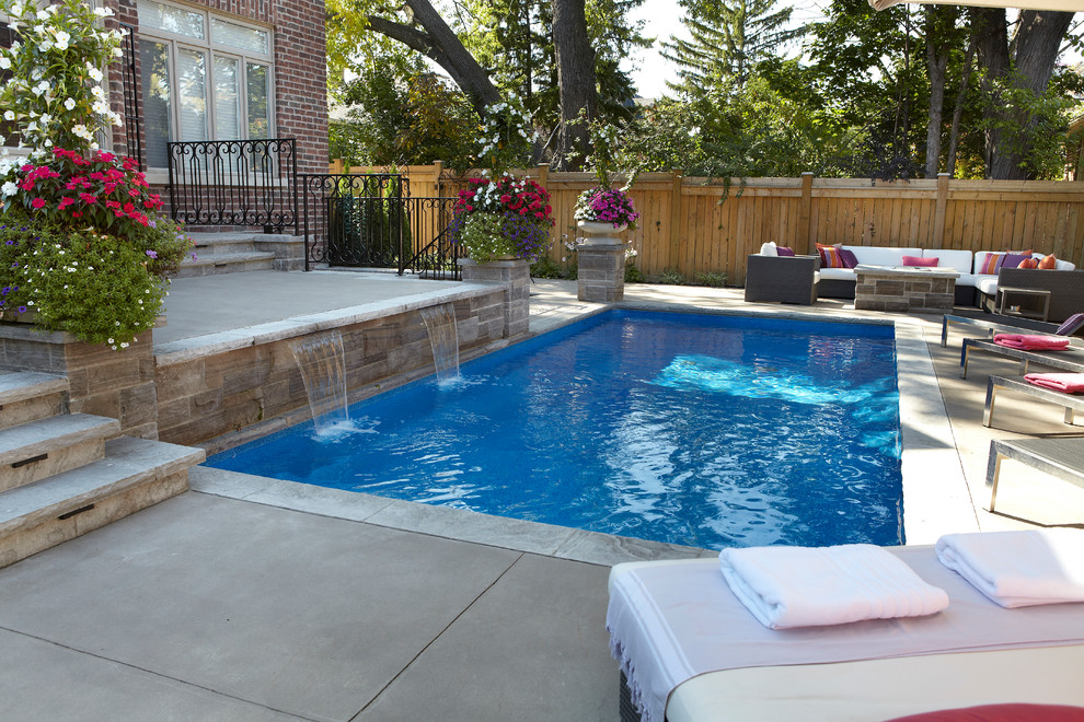Example of a mid-sized trendy backyard concrete paver and rectangular lap pool fountain design in Toronto