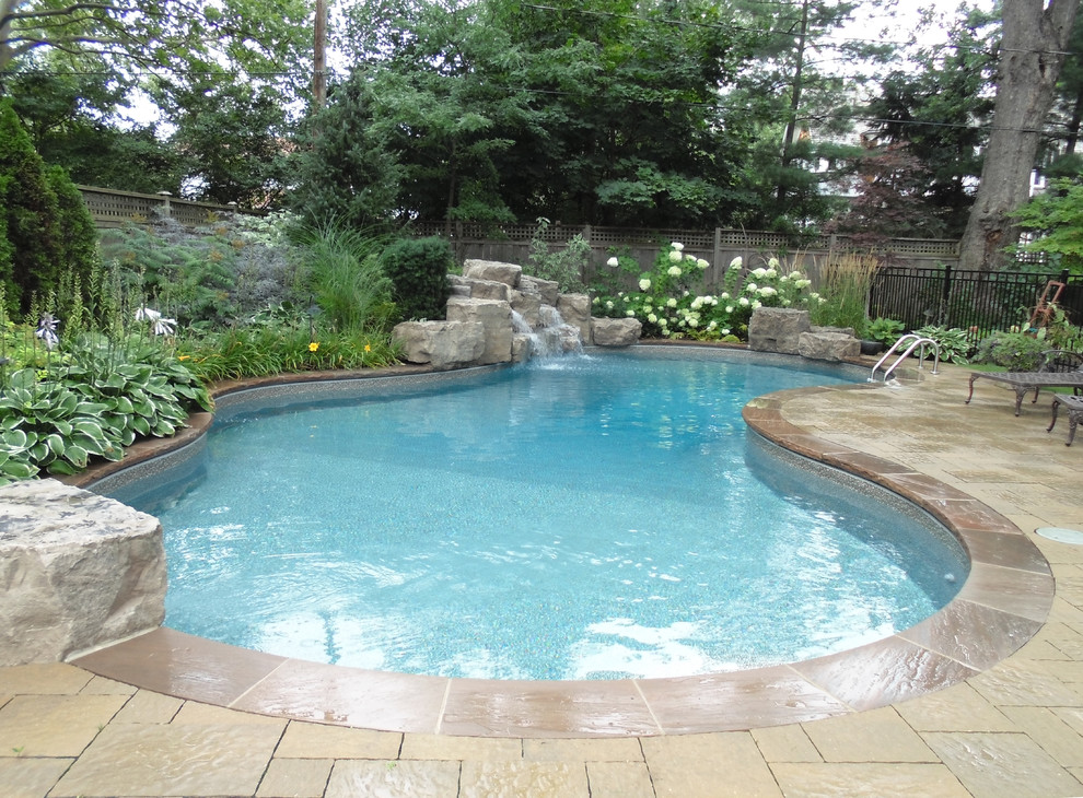 Medium sized classic custom shaped swimming pool in Toronto with a water feature.