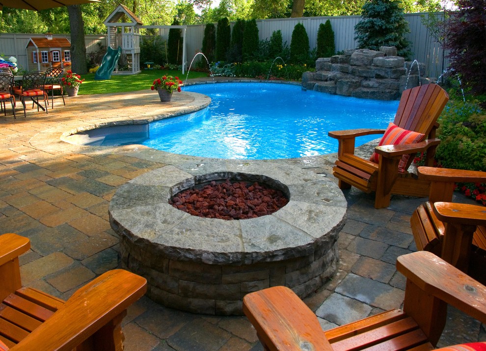 Modelo de piscina con fuente bohemia a medida en patio trasero con adoquines de hormigón