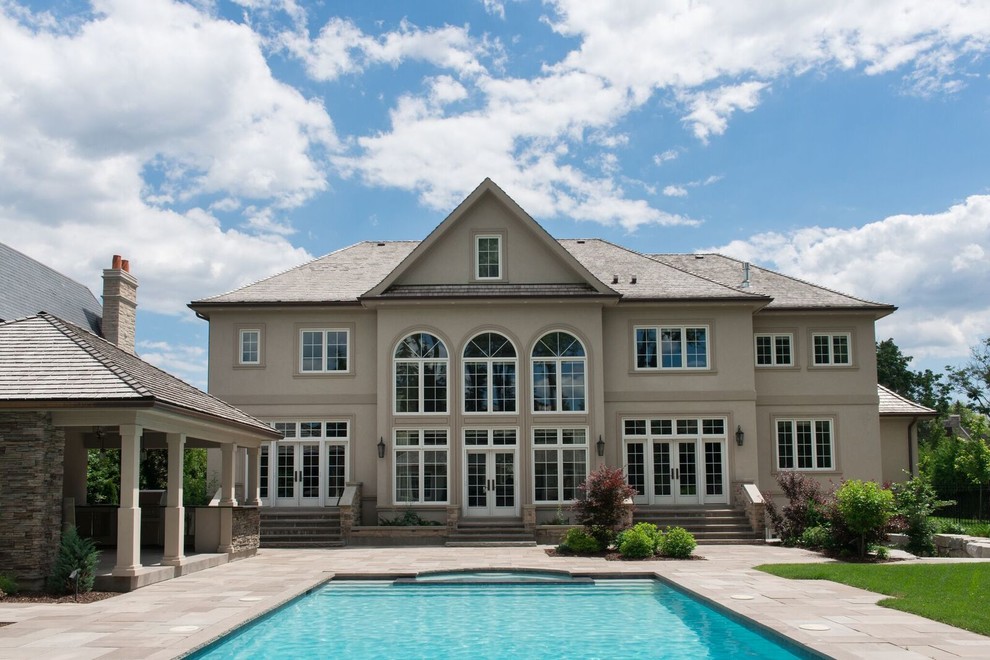 Imagen de casa de la piscina y piscina alargada clásica grande rectangular en patio trasero con losas de hormigón