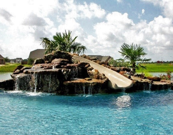 На фото: большой естественный бассейн произвольной формы на заднем дворе в стиле модернизм с водной горкой и покрытием из декоративного бетона