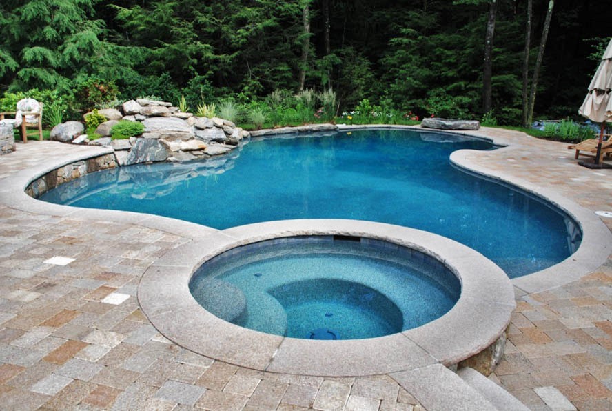 Idee per una grande piscina minimalista personalizzata dietro casa con una vasca idromassaggio e cemento stampato