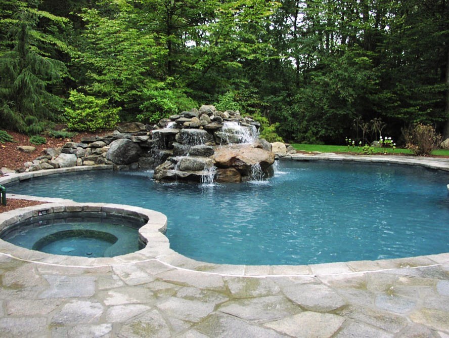 Aménagement d'une grande piscine arrière moderne sur mesure avec un bain bouillonnant et du béton estampé.