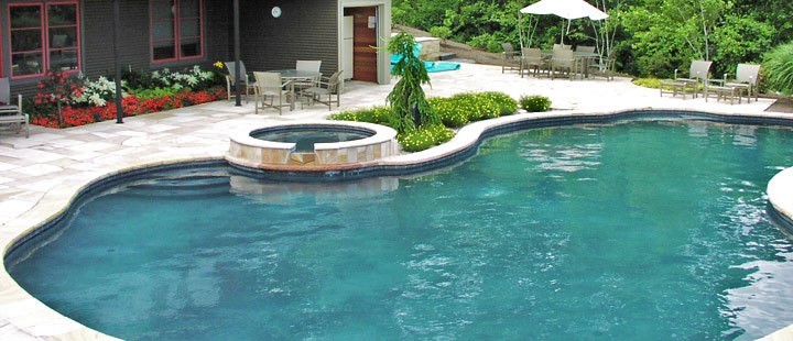 Immagine di una grande piscina moderna personalizzata dietro casa con una vasca idromassaggio e cemento stampato