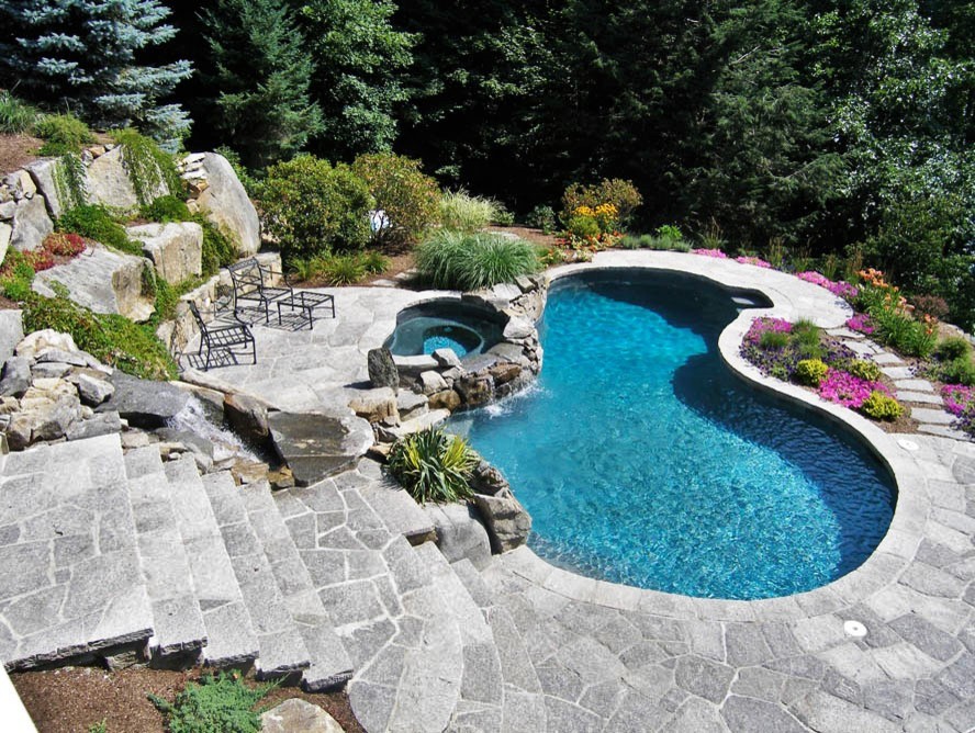 Inspiration för en stor funkis anpassad pool på baksidan av huset, med spabad och stämplad betong