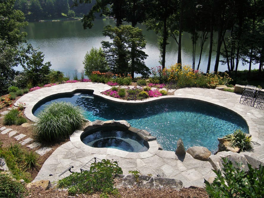 Immagine di una grande piscina moderna personalizzata dietro casa con una vasca idromassaggio e cemento stampato
