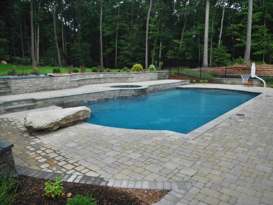 Large minimalist backyard stamped concrete and custom-shaped hot tub photo in New York