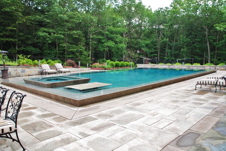 Idée de décoration pour une grande piscine arrière minimaliste sur mesure avec un bain bouillonnant et du béton estampé.