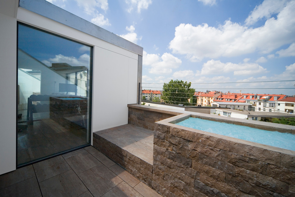 Diseño de piscina elevada contemporánea pequeña rectangular en azotea con adoquines de piedra natural