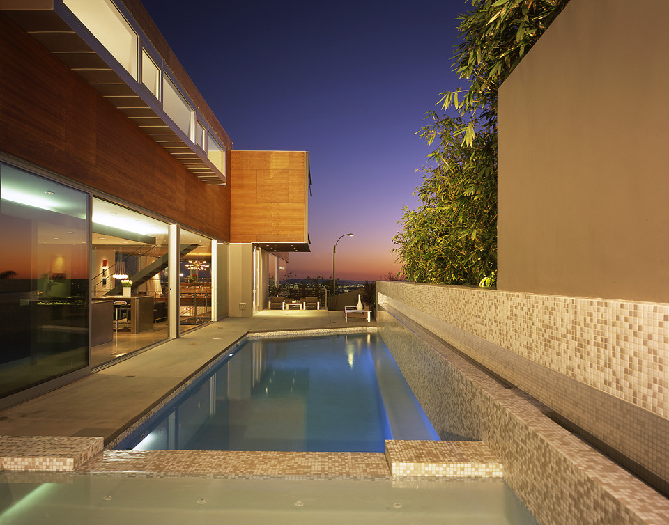 Esempio di un'ampia piscina monocorsia moderna rettangolare dietro casa con una vasca idromassaggio e pavimentazioni in cemento