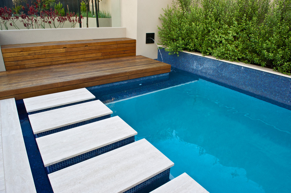 Modelo de piscina contemporánea de tamaño medio rectangular en patio trasero con adoquines de piedra natural