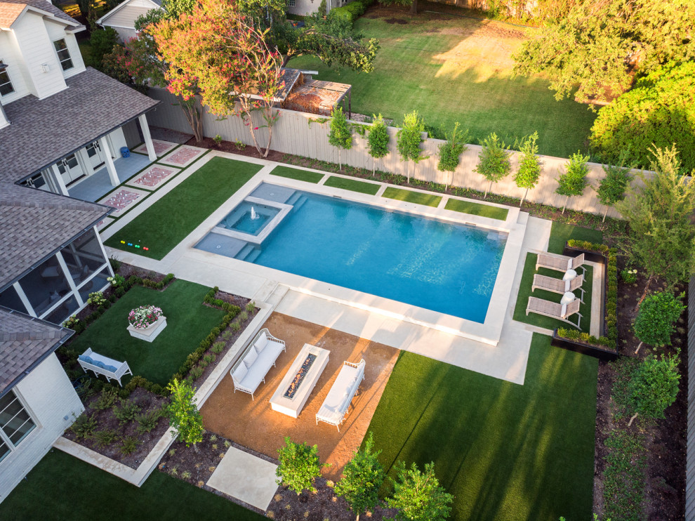 Foto de piscina tradicional renovada grande rectangular en patio trasero con paisajismo de piscina y losas de hormigón