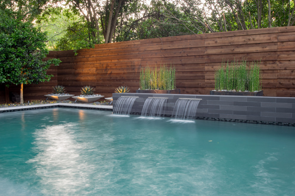 Design ideas for a small modern back private and custom shaped swimming pool in Dallas with natural stone paving.