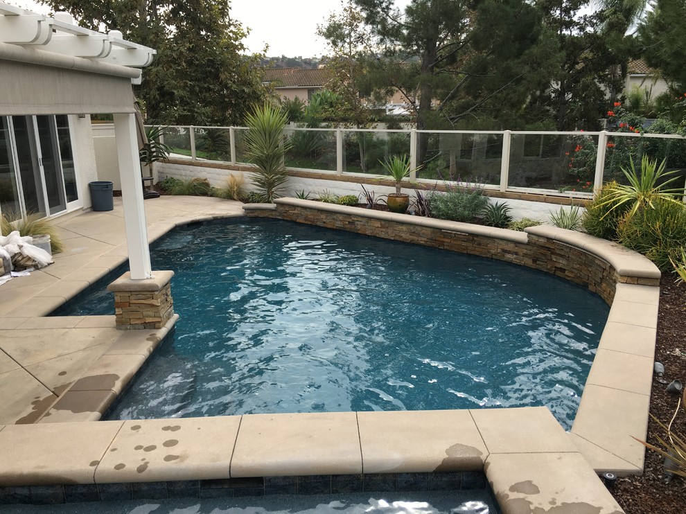 Ejemplo de piscinas y jacuzzis alargados tropicales de tamaño medio a medida en patio trasero con losas de hormigón
