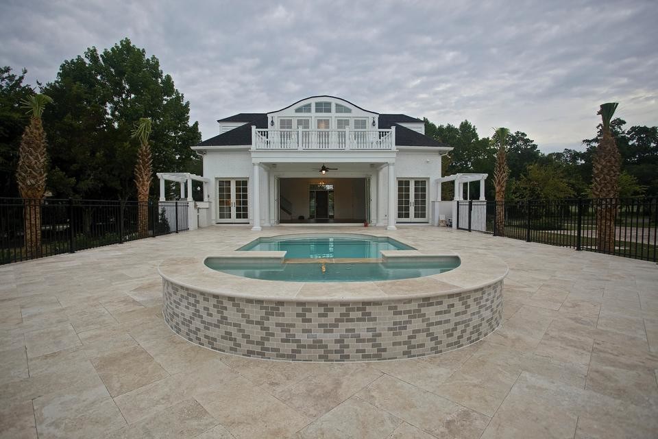 Immagine di una piscina naturale chic personalizzata dietro casa con pavimentazioni in pietra naturale e una vasca idromassaggio