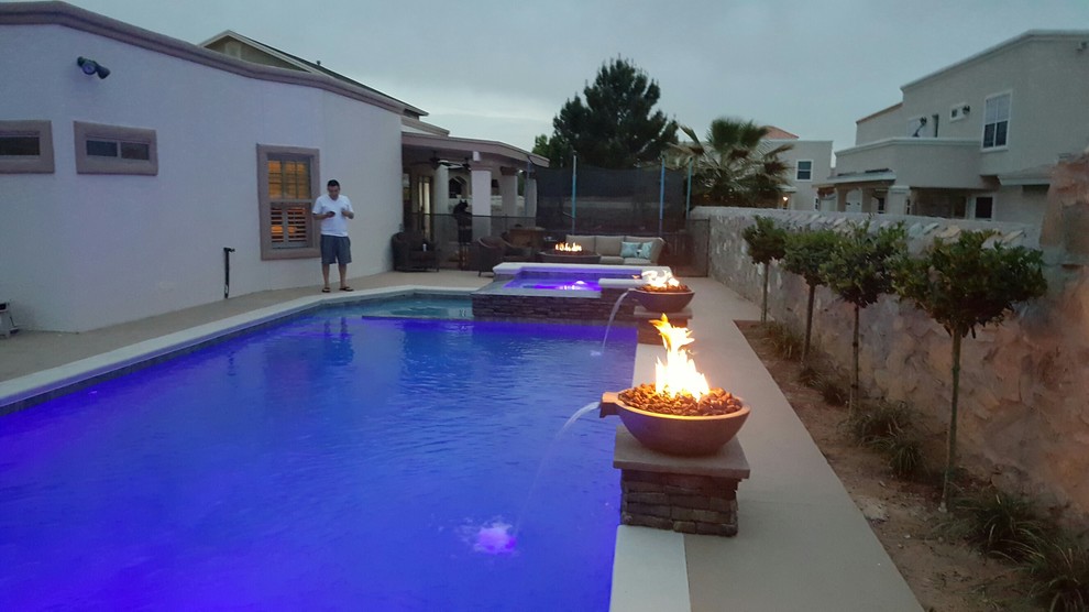 Modelo de piscina con fuente natural moderna grande a medida en patio trasero con losas de hormigón