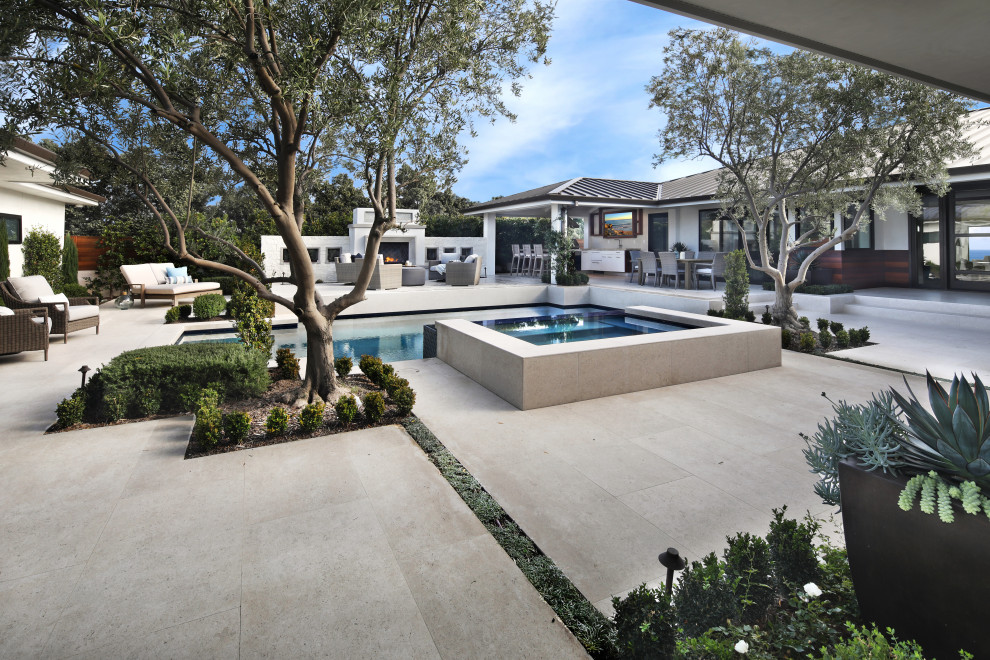 На фото: большой прямоугольный бассейн-инфинити на внутреннем дворе в современном стиле с джакузи и покрытием из каменной брусчатки с