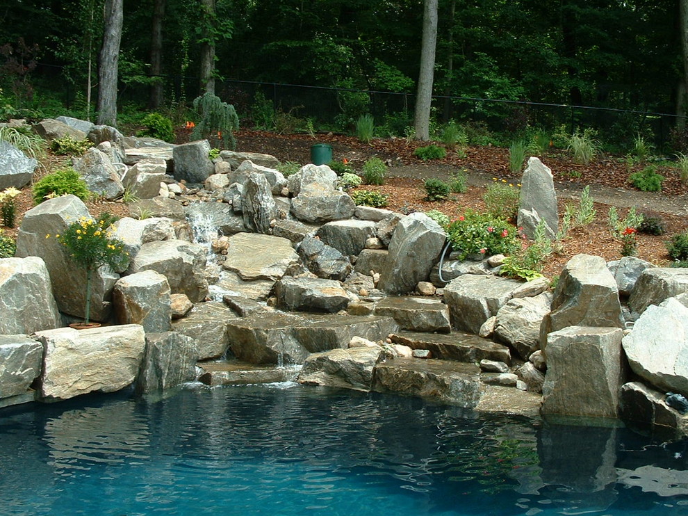 Imagen de piscina con fuente natural de estilo americano grande a medida en patio trasero con adoquines de piedra natural