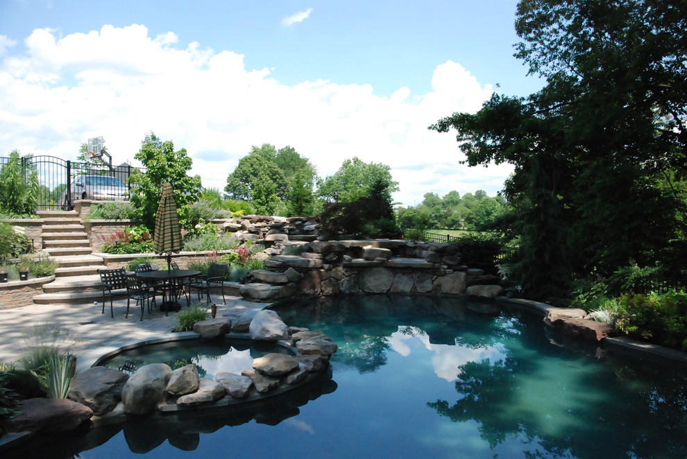 Example of a large minimalist backyard concrete paver and custom-shaped natural pool fountain design in DC Metro